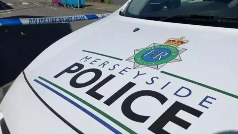 The bonnet of a Merseyside Police car bearing Merseyside Police's logo against a white background