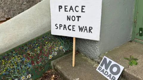 Picture of placards reading 'Peace not space war' and 'no radar' 