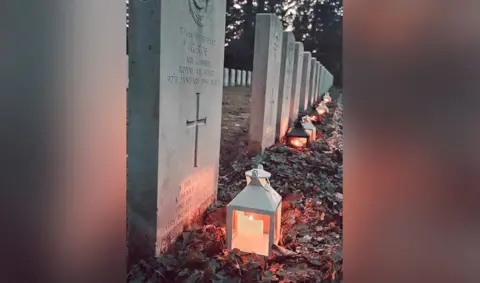 Supplied A grave stone with a candle light next to it 