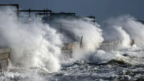 Getty Images Aggressive waves battering against a wall during a storm.