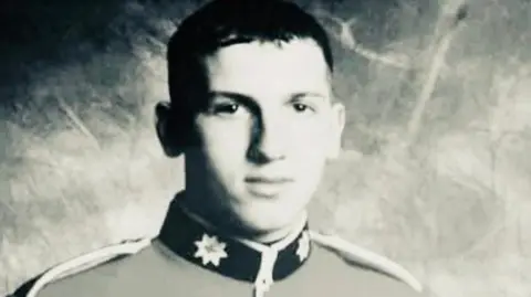 A black and white, head and shoulders photo of Alan Forcer in military uniform. He has short dark hair.