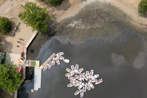 EPA An aerial view taken with a drone shows rental rowing boats floating past a dried-up section of Hollow Pond in east London, Britain, 22 July 2026.