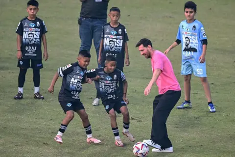 AFP via Getty Image Argentina's footballer Lionel Messi (2R) plays football with children during his GOAT Tour at the Arun Jaitley Stadium in New Delhi on December 15, 2025. The 38-year-old Argentina and Inter Miami superstar Messi, along with his Inter Miami teammates Luis Suarez and Rodrigo de Paul, are part of a so-called GOAT Tour of a cricket-crazy nation. (Photo by Sajjad HUSSAIN / AFP via Getty Images)