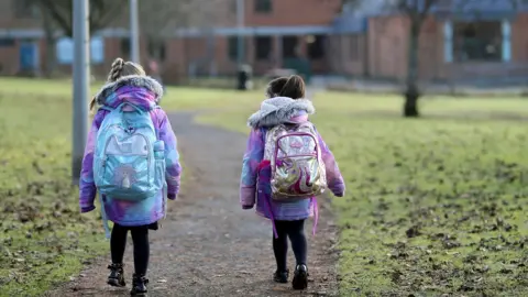 Reuters two young schoolgirls with backpacks walk towards a school when restrictions were relaxed in 2021