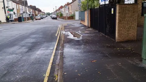 North East Lincolnshire Council A photo of Armstrong Street showing a road with yellow road markings and a path. In the distance are residential houses with cars parked on the street.