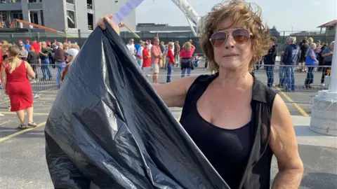 A woman holds a garbage bag