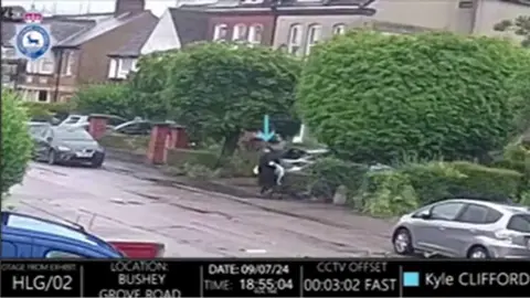 Gambar CCTV Polisi Hertfordshire menunjukkan sosok yang berpakaian hitam berjalan di sepanjang jalan pinggiran kota membawa selimut putih dengan sesuatu di bawahnya.