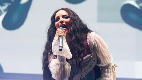 Getty Images Music artist Jade, singing into a microphone, while wearing a white sleeved outfit,