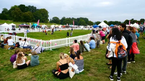 Dogfest Dozens of people sit around a performance area bordered by a white picket-style fence at Dogfest in Bristol