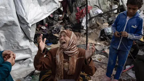EPA A Palestinian woman reacts next to tents destroyed by a fire triggered by an Israeli air strike in western Rafah on Sunday, in the southern Gaza Strip (28 May 2024)