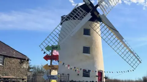 An old white windmill with bunting on it