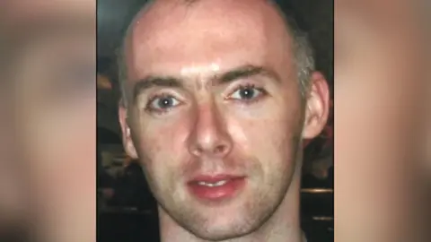 McKevitt family A cropped picture of John Paul McKevitt, with a blurred background. He is looking down the camera. He has short greying hair.