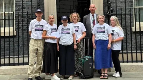 Lobular Moon Shot Six women wearing Lobular Moon Shot t-shirts and a man wearing a grey suit and a red tie stand on the steps of 10 Downing Street.