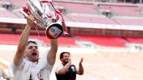 Nick Tsaroulla lifts the League Two play-off trophy