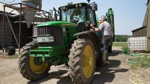 Julian climbs inside his tractor.