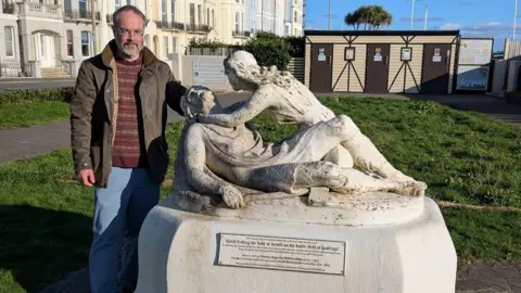 UEA Prof Tom Licence is standing near the statue of Harold and Edith at West Marine Gardens. The sculpture shows Edith Swanneck finding the body of her husband, King Harold Godwinson, on the field of the Battle of Hastings in 1066, and stands a few miles from the battlefield.