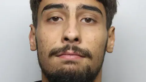 A custody photo of a man with brown eyes, short brown hair and facial hair