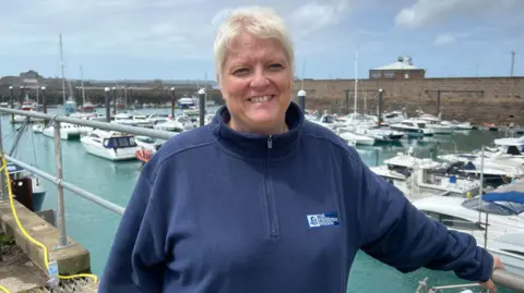 A woman standing at the edge of the pier smiling to the camera.
