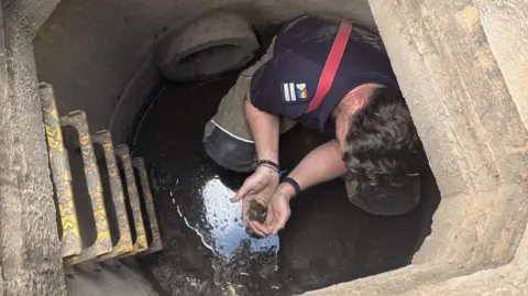 Steve Bonnington Firefighter down a large drain holding duckling, pictured from above
