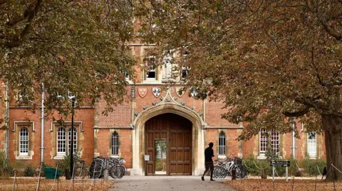AFP via Getty Images The door of Jesus College at the University of Cambridge surrounded by trees. 