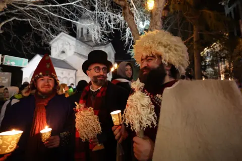 AFP Orang-orang yang memegang lilin berkumpul untuk merayakan malam Natal Ortodoks di sepanjang Rustaveli Avenue, di pusat Tbilisi pada 6 Januari 2025.