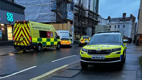 The picture of the scene at Regent Street, Plymouth. Numerous emergency service vehicles are parked out the front of properties. 