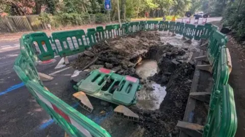 Roadworks at Deepcut Bridge Road in Surrey. Green plastic fencing around a water leak.