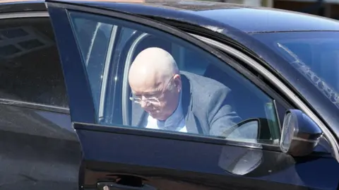 PA Media Peter Murrell gets out of a black car in April 2023. He is wearing a grey jacket and white shirt.