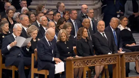 All five living former US presidents sit in the pews of a church.