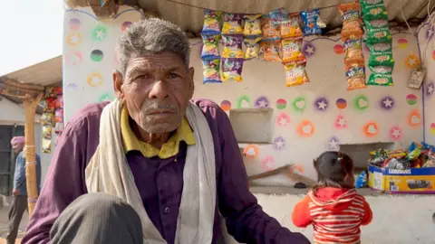 A man poses in front of his shop in a village in Bundelkhand region of MP