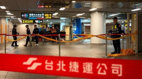 EPA/Shutterstock Red tape at a train station with several police officers 