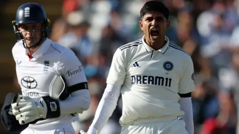 Shubman Gill roars with delight after reaching his century, with England wicketkeeper Jamie Smith watching on