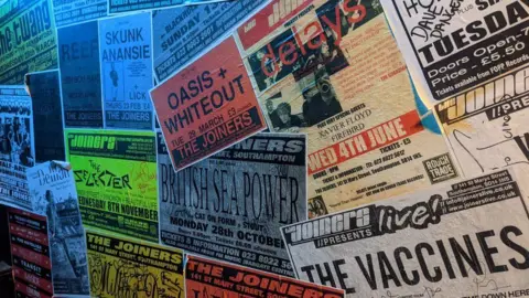 The Joiners, Southampton A wall covered in gig posters, with a red Oasis & Whiteout one in the middle, advertising tickets for £3 at The Joiners in Southampton