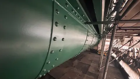 A close up of the metal work of the Tyne Bridge. It has had a fresh coat of dark green paint. Scaffolding has also been erected around the bridge.