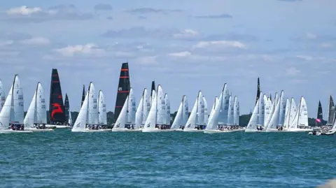 Cowes Week Martin Allen A large fleet of sailing yachts spread across the Solent during a race at Cowes Week.