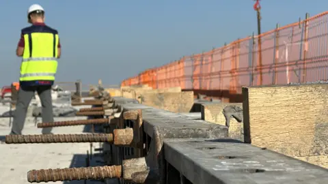 A worker stands at a construction site for Rail Baltica