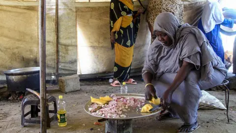 AFP / Getty Images a woman sits low in front of the stove and cooks in a camp for the displaced.