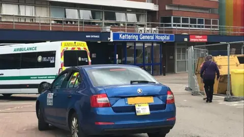 BBC Entrance to Kettering General Hospital with taxi in the foreground