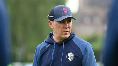 Ryan Campbell wearing a Durham two-tone blue hoodie and a Durham cap with sunglasses on the back of his cap