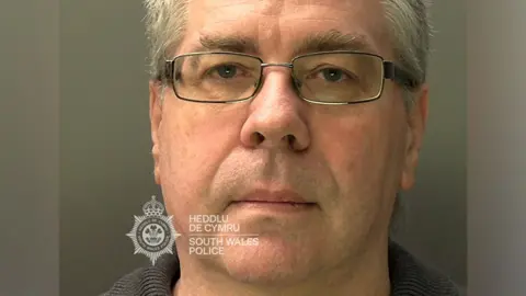 A mugshot of Christopher Phillips, who has grey hair and glasses