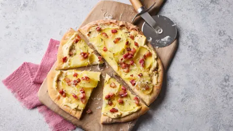 A top-down image shoing a pizza cut into slices on a table.