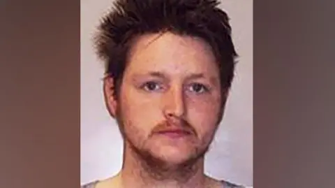 Police Scotland Jamie Forbes, man with thin mustache and stubble looks into the camera