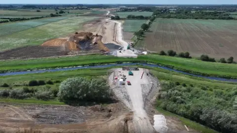 An aerial shot of two new roads on either side of the River Witham. Fields surround the roads and river. 