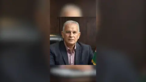 Mohammed Al-Wahidi has short grey hair. He is wearing a dark suit jacket and a pale pink shirt.