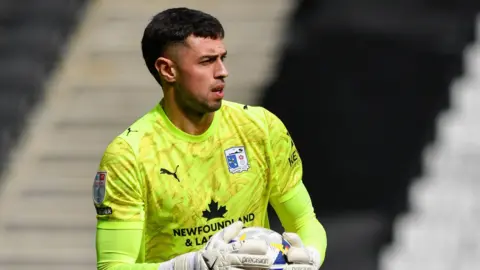 Wyll Stanway wearing a lime green goalkeeper kit for Barrow