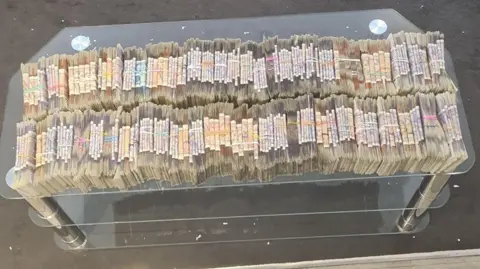 Nottinghamshire Police A table is covered in tightly packed wads of banknotes