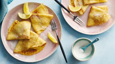 Tho plates of flat pancakes with lemon and white sugar