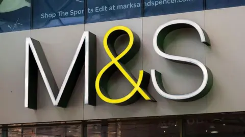 Getty Images A sign for M&S hangs outside a storefront on a grey wall