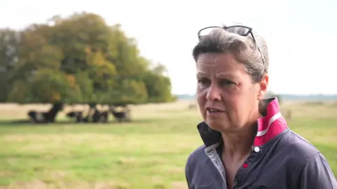 Farmer Nicola Chapman standing in a field with cows in the background