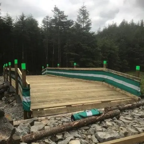 FLS A wooden bridge being constructed with wooden logs around it